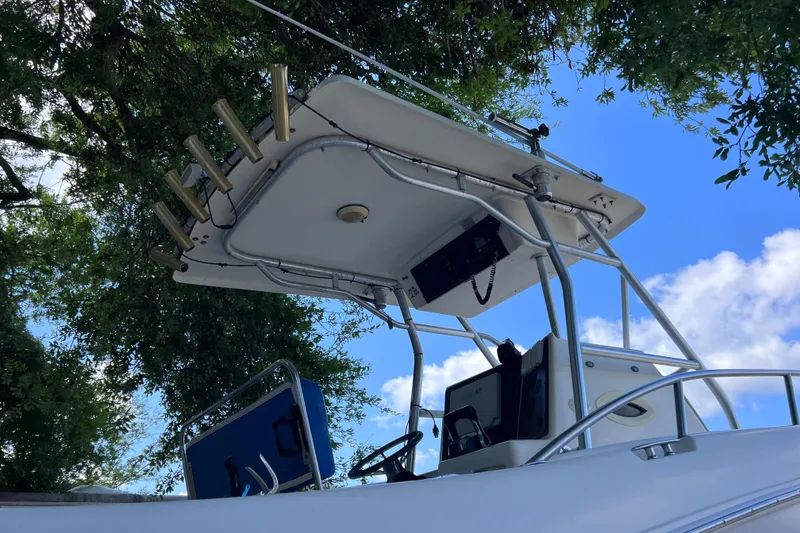 Slide: The Image of 1999 World Cat 246 SF boat helm with rod holders, under a clear blue sky. - 8