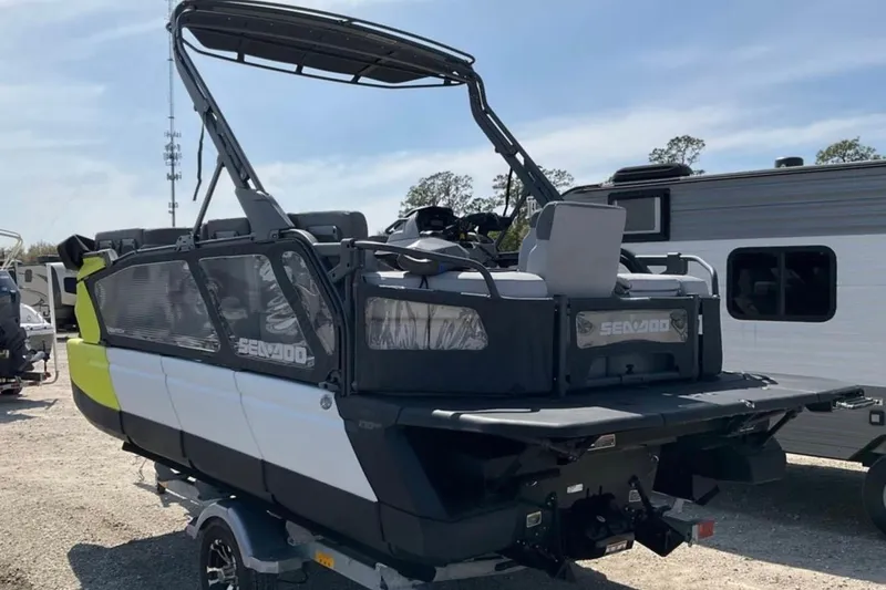Slide: The Image of 2024 Sea-Doo Switch Cruise 18 pontoon boat on trailer, parked outdoors. - 2