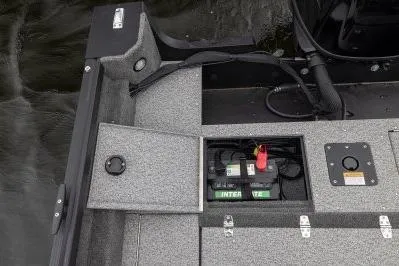 Slide: The Image of 2026 Alumacraft Voyageur 175 Sport boat battery compartment with open hatch on water. - 14