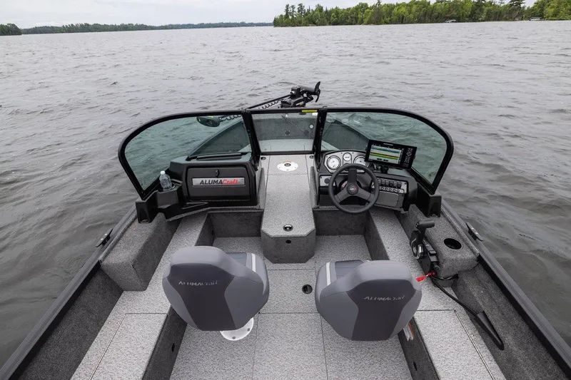 Slide: The Image of 2026 Alumacraft Voyageur 175 Sport boat interior with steering wheel and dashboard on a lake. - 16