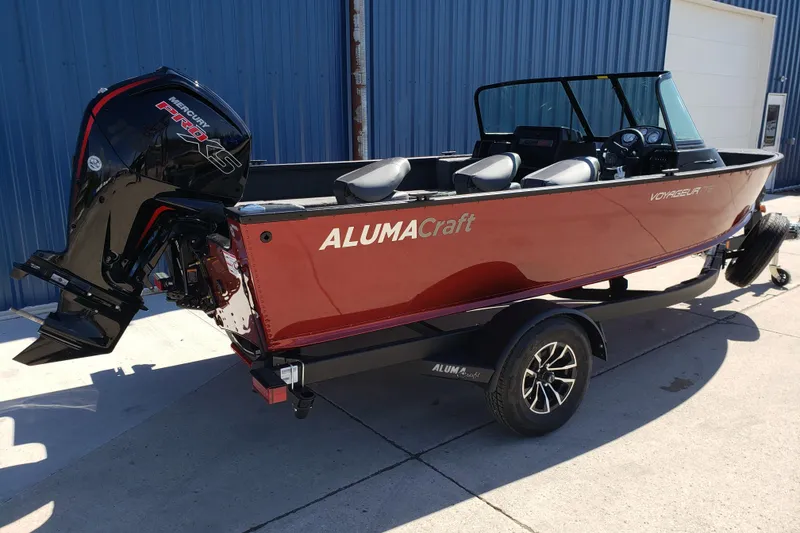 Slide: The Image of 2026 Alumacraft Voyageur 175 Sport boat with Mercury Pro XS engine, parked outdoors. - 2