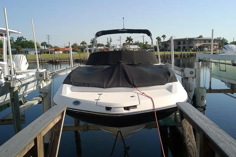 Slide: The Image of 2021 Hurricane SunDeck 2410 OB boat docked, covered, in a serene marina setting. - 1