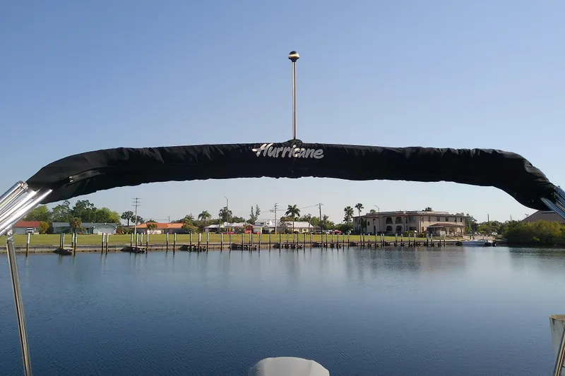 Slide: The Image of 2021 Hurricane SunDeck 2410 OB boat on calm water with scenic waterfront view. - 24