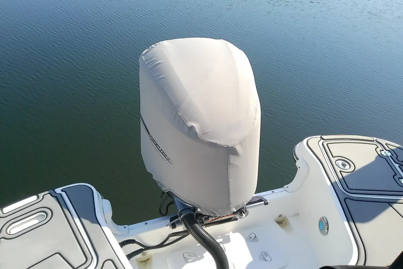 Slide: The Image of 2021 Hurricane SunDeck 2410 OB boat engine covered, docked on calm water. - 33