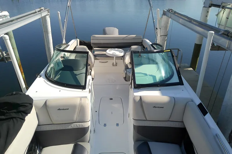 Slide: The Image of 2021 Hurricane SunDeck 2410 OB boat interior with seating and table, docked on calm water. - 7