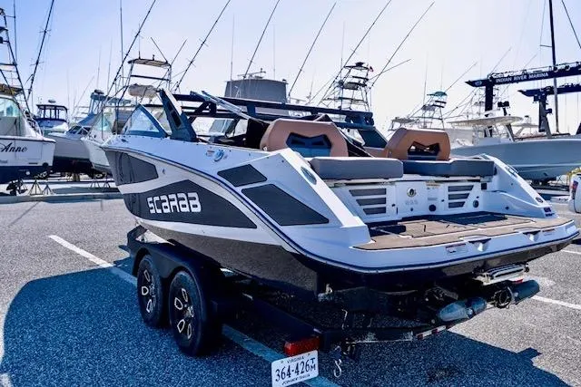 Slide: The Image of 2024 Scarab 235 ID boat on trailer in marina parking lot. - 12