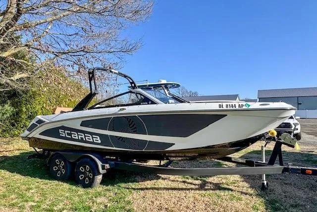 Slide: The Image of 2024 Scarab 235 ID boat on trailer, parked outdoors, showcasing sleek design and modern features. - 3