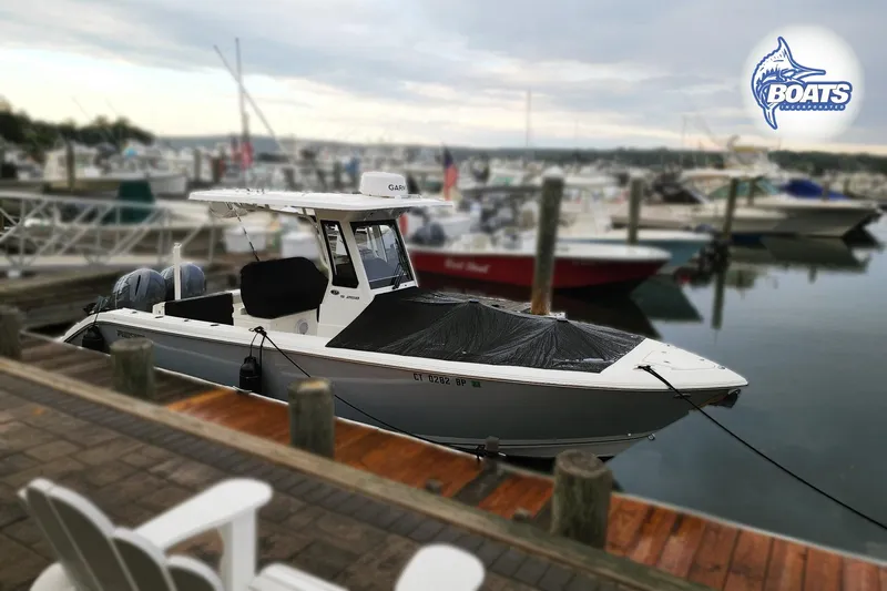 Slide: The Image of 2022 Pursuit S 268 Sport boat docked at a marina with other vessels. - 2