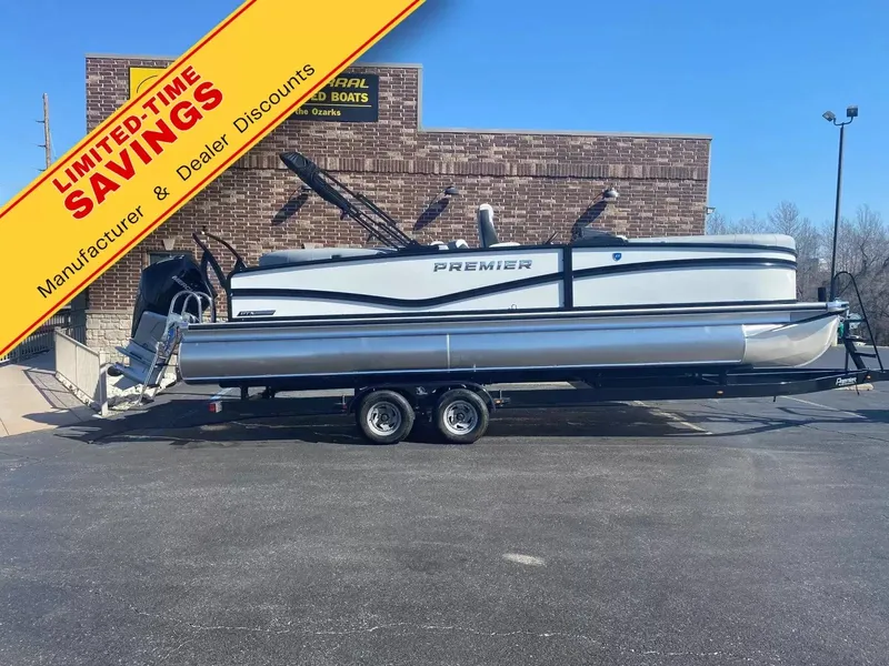 The Image of A Premier 250 Solaris RF pontoon boat is on a trailer in front of a brick building. - 1
