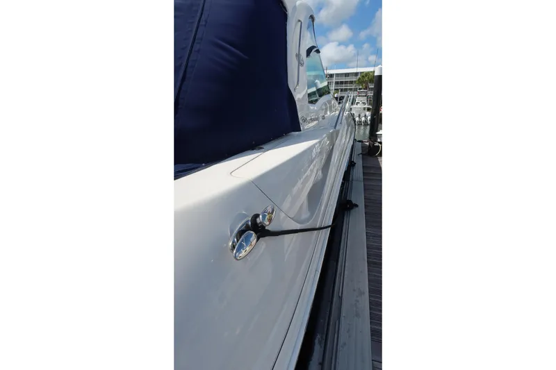 Slide: The Image of 2005 Sea Ray 500 Sundancer yacht docked, showcasing sleek white hull and blue cover. - 2