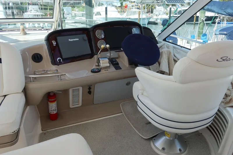 Slide: The Image of 2005 Sea Ray 500 Sundancer helm with navigation equipment and captain's chair in marina setting. - 3