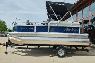 The Image of 2026 Sun Tracker Bass Buggy 16 XL Select pontoon boat on trailer, parked outdoors. - 0