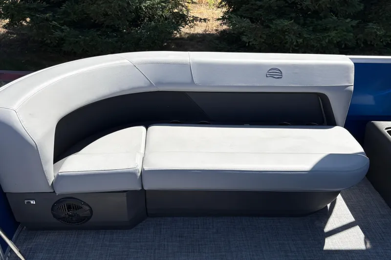Slide: The Image of 2026 Sun Tracker Party Barge 16 DLX seating area with gray upholstery and speaker. - 16