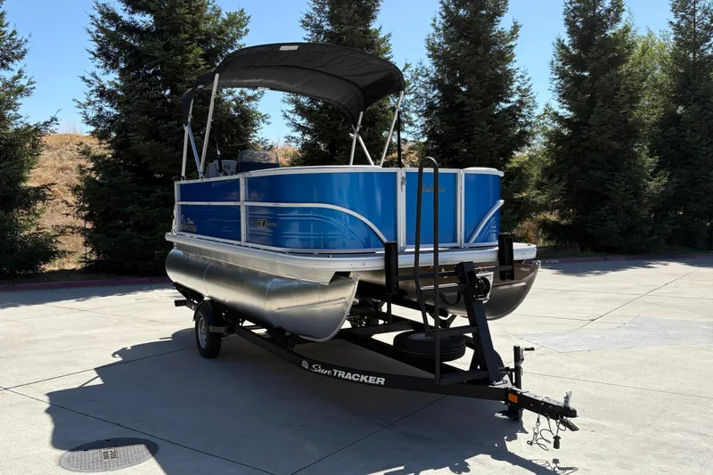 Slide: The Image of 2026 Sun Tracker Party Barge 16 DLX pontoon boat on trailer, parked outdoors. - 11