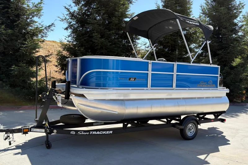 Slide: The Image of 2026 Sun Tracker Party Barge 16 DLX pontoon boat on trailer, parked outdoors. - 10