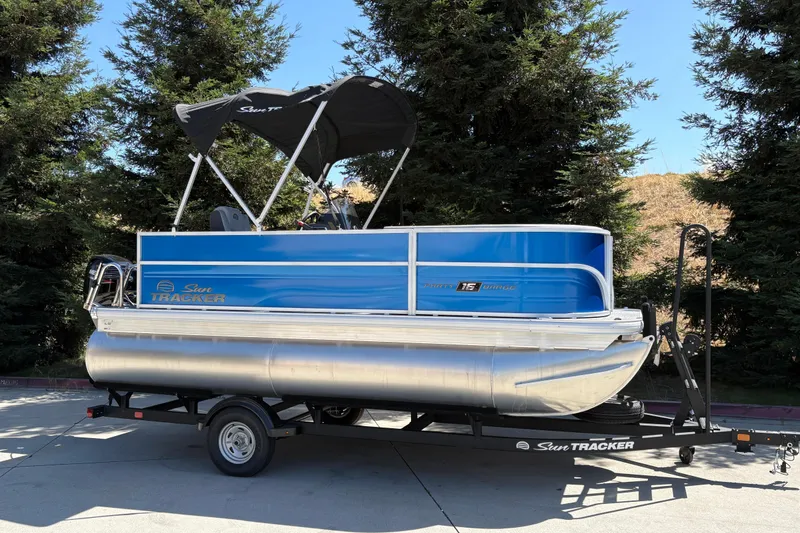 Slide: The Image of 2026 Sun Tracker Party Barge 16 DLX pontoon boat on trailer, parked outdoors. - 3
