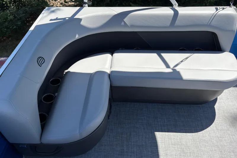 Slide: The Image of 2026 Sun Tracker Party Barge 16 DLX seating area with cup holders and gray upholstery. - 26