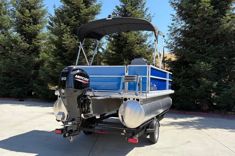 Slide: The Image of 2026 Sun Tracker Party Barge 16 DLX pontoon boat with Mercury 50 engine, parked outdoors. - 5