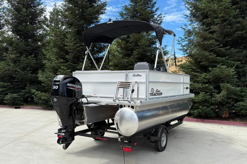 Slide: The Image of 2026 Sun Tracker Party Barge 16 DLX pontoon boat with Mercury 50 engine, parked outdoors. - 23