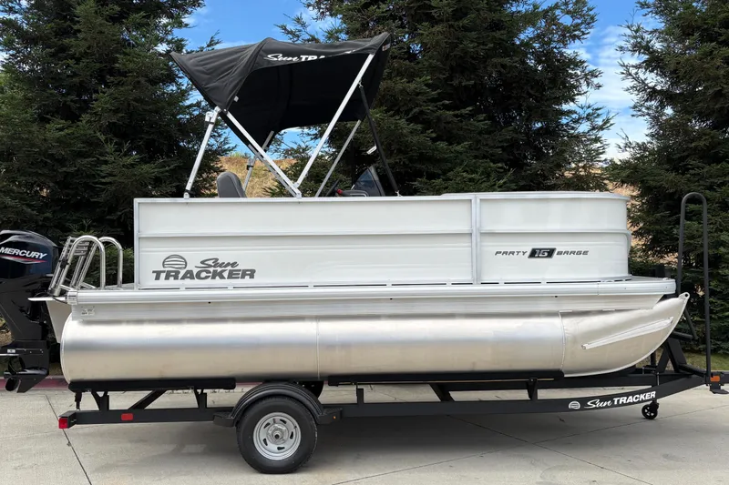 The Image of 2026 Sun Tracker Party Barge 16 DLX pontoon boat on trailer, parked outdoors. - 0