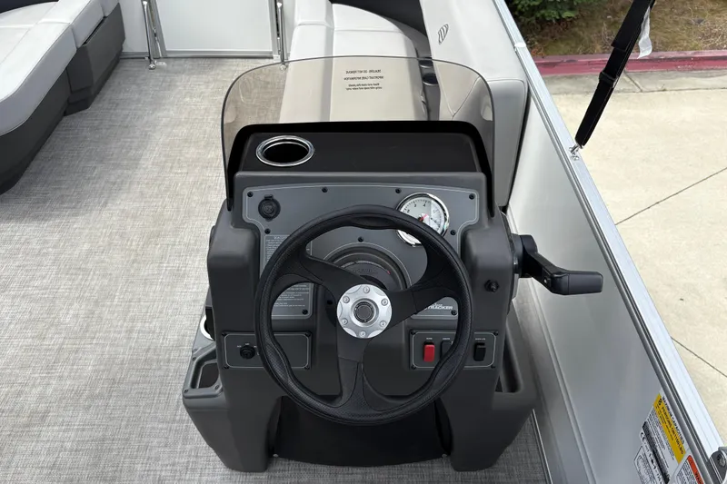 Slide: The Image of 2026 Sun Tracker Party Barge 16 DLX steering console with gauges and cup holder. - 16