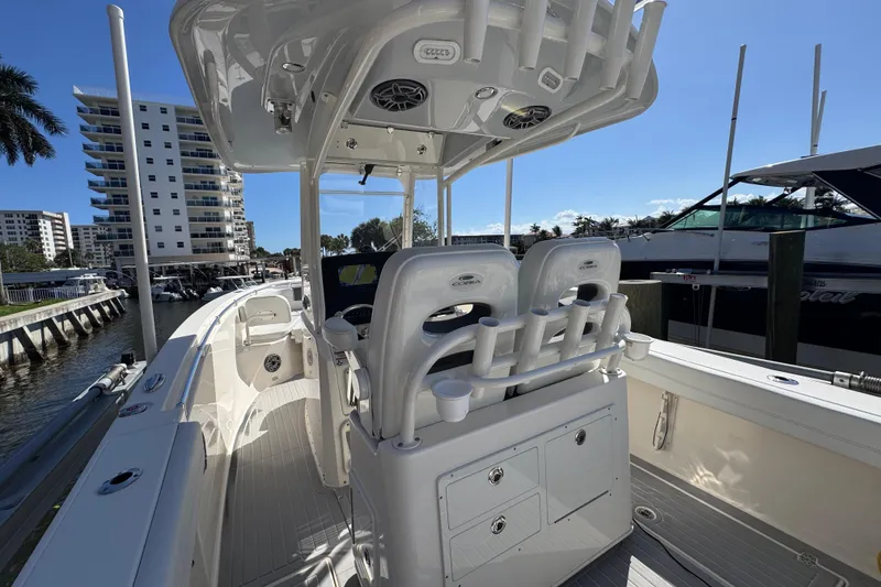 Slide: The Image of 2023 Cobia 280 Center Console boat interior with seating and storage, docked near waterfront buildings. - 11