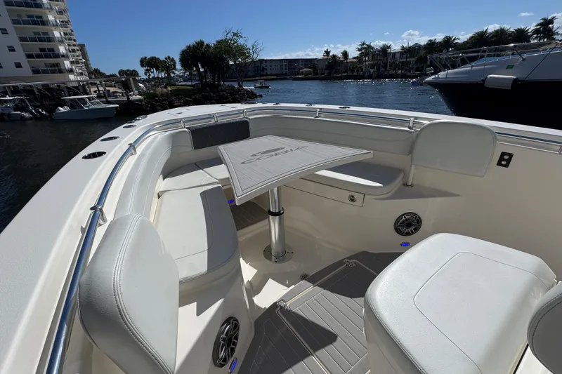Slide: The Image of 2023 Cobia 280 Center Console boat interior with seating and table, docked by waterfront. - 19