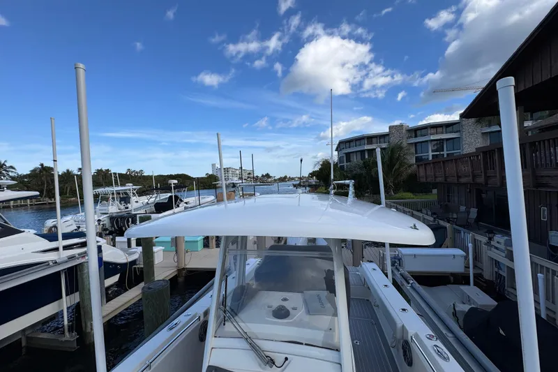 Slide: The Image of 2023 Cobia 280 Center Console boat docked at marina under blue sky. - 25