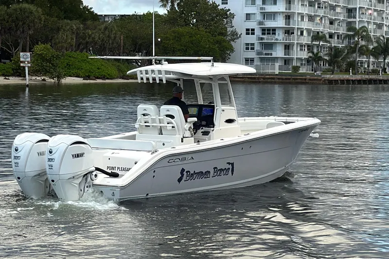 Slide: The Image of 2023 Cobia 280 Center Console boat cruising on water with twin Yamaha engines. - 3