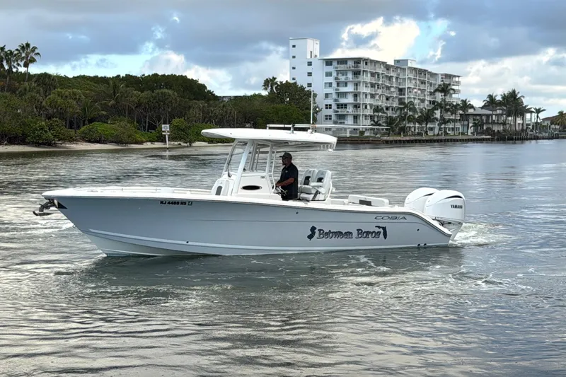Slide: The Image of 2023 Cobia 280 Center Console boat cruising on a calm waterway near a residential area. - 4