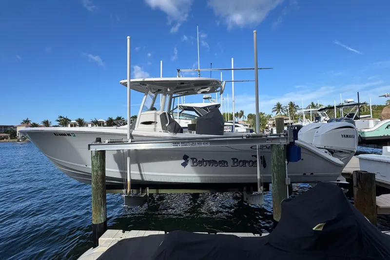 Slide: The Image of 2023 Cobia 280 Center Console boat docked at marina under clear blue sky. - 5