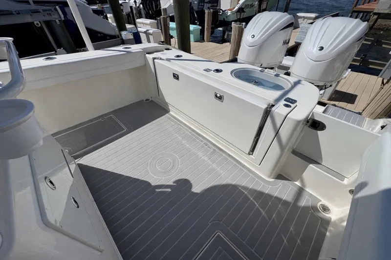 Slide: The Image of 2023 Cobia 280 Center Console boat deck with twin engines and storage compartments. - 9