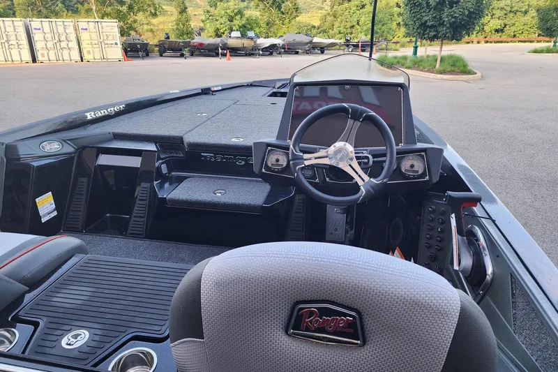 Slide: The Image of 2026 Ranger Z518 boat interior with steering wheel and dashboard, parked outdoors. - 2