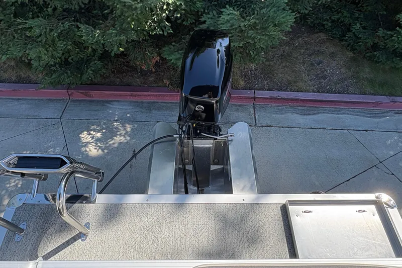 Slide: The Image of 2026 Sun Tracker Bass Buggy 16 XL Select pontoon boat with outboard motor, parked on pavement. - 4