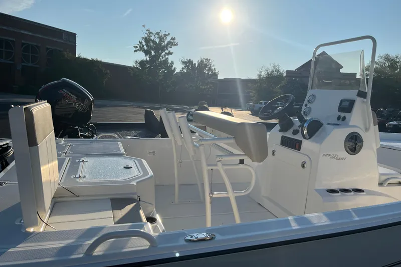 Slide: The Image of 2026 Mako Pro Skiff 19 CC boat interior with console and seating, under bright sunlight. - 2