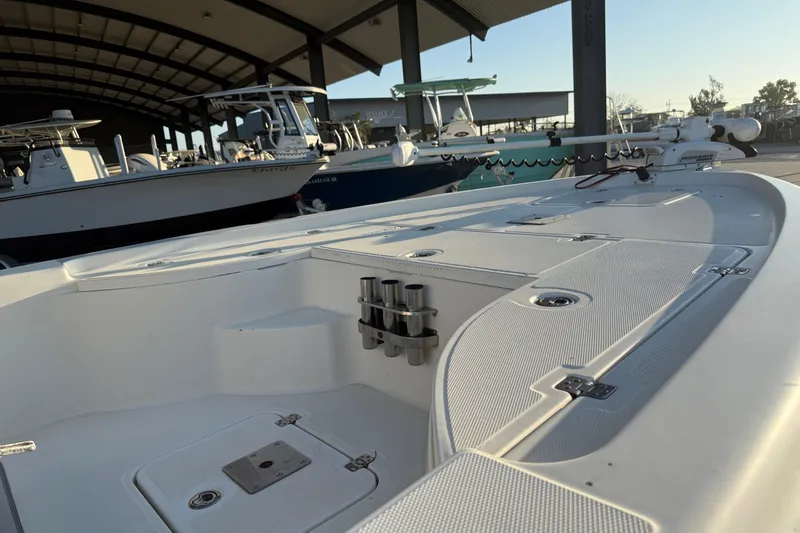 Slide: The Image of 2006 Triton 240 LTS boat in marina, showcasing deck and rod holders. - 10