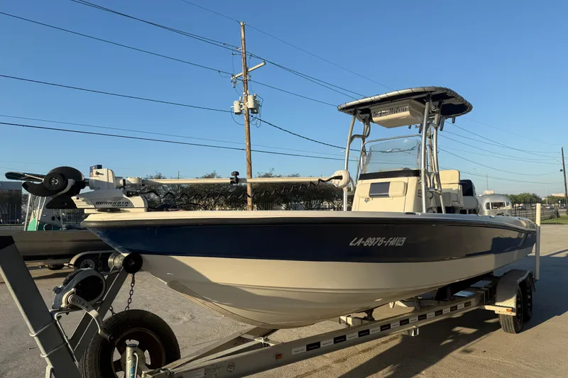 Slide: The Image of 2006 Triton 240 LTS boat on trailer, parked outdoors under clear blue sky. - 4