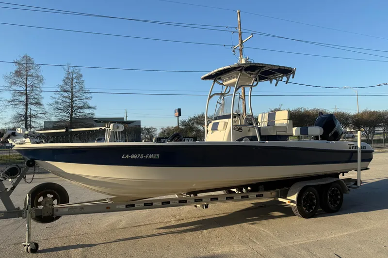 Slide: The Image of 2006 Triton 240 LTS boat on trailer, parked outdoors under clear sky. - 5