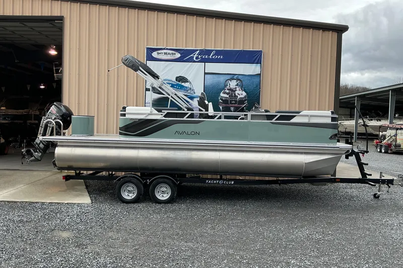 The Image of 2026 Avalon Venture Quad Lounge 22' pontoon boat on trailer outside dealership. - 1