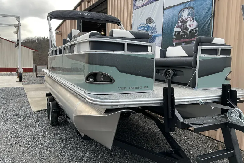 Slide: The Image of 2026 Avalon Venture Quad Lounge 22' pontoon boat on trailer, parked outside a building. - 3