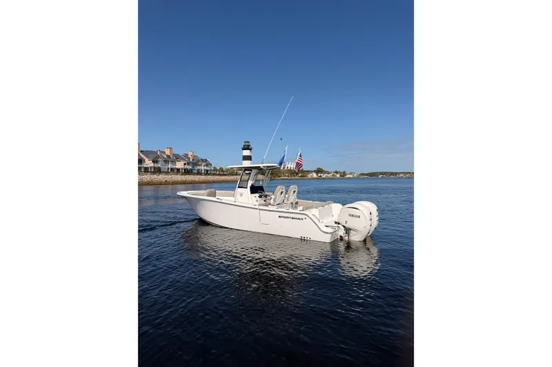 The Image of 2025 Sportsman Open 262 Center Console boat on calm water near coastal homes. - 0