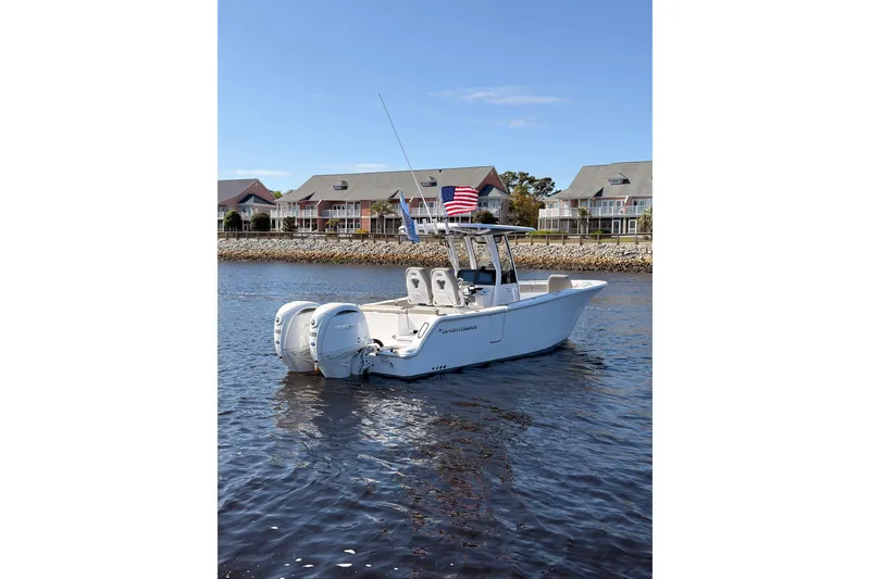 Slide: The Image of 2025 Sportsman Open 262 Center Console boat on water, American flag, coastal homes in background. - 2