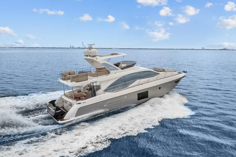 Slide: The Image of 2019 Azimut 55 yacht cruising on open water under a clear blue sky. - 2
