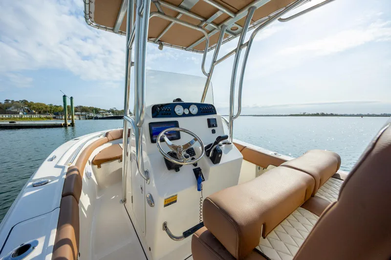 Slide: The Image of 2022 Pioneer 202 Islander boat interior with steering console and seating, on calm water. - 13