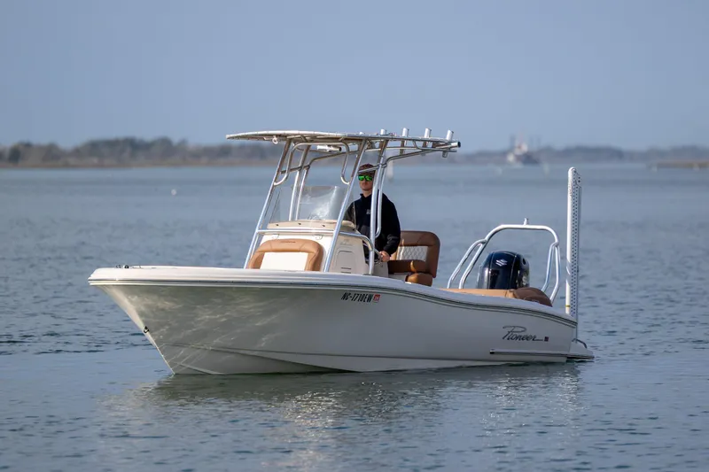 Slide: The Image of 2022 Pioneer 202 Islander boat cruising on calm waters with a person at the helm. - 8