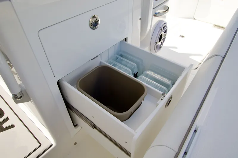 Slide: The Image of An open cabinet with a trash bin and several compartments on a boat. - 27