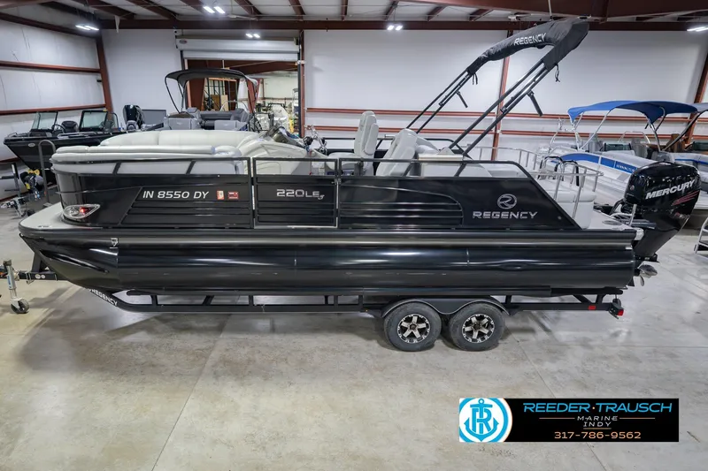 The Image of 2017 Bennington 220 LE3 pontoon boat in showroom, featuring sleek black design and Mercury engine. - 2