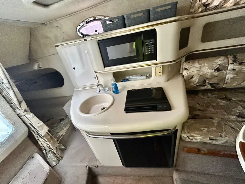 Slide: The Image of 1999 Sea Ray 270 Sundancer cabin interior with kitchenette, microwave, and seating area. - 13