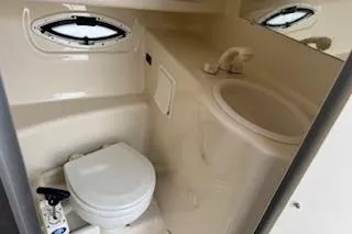 Slide: The Image of 2001 Maxum 2400 SCR boat bathroom with toilet, sink, and porthole window. - 13