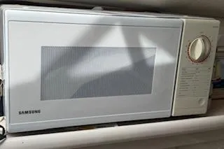 Slide: The Image of White Samsung microwave with dial control on a kitchen shelf. - 9